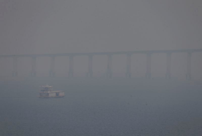 A boat navigates the Negro River amid smoke from wildfires in Manaus, Amazonas state, Brazil, Tuesday, Aug. 27, 2024. (AP Photo/Edmar Barros)