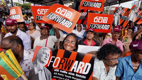 A woman supporter of Sri Lankan President and independent presidential candidate Ranil Wickremesinghe, holds a placard at an election rally in Minuwangoda, Sri Lanka, Tuesday, Sept. 17, 2024. (AP Photo/Rajesh Kumar Singh)