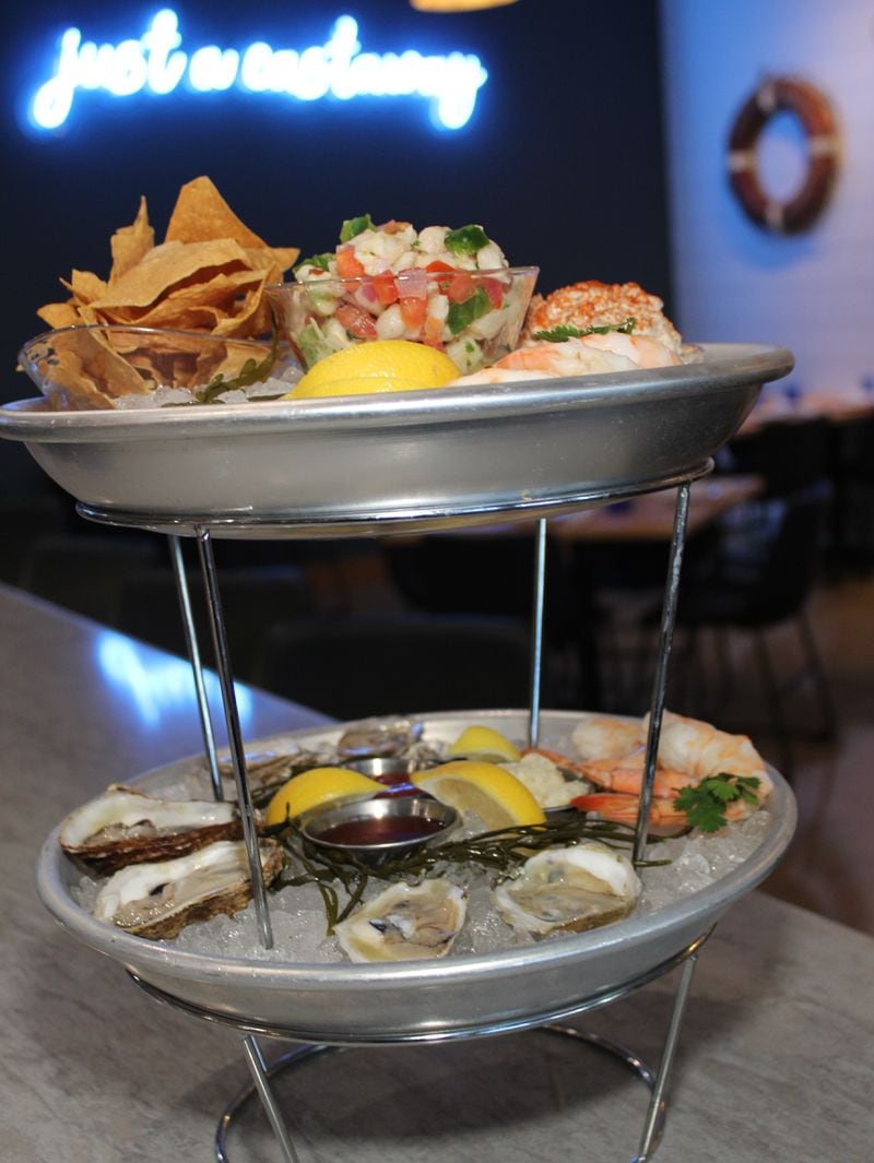 Behind this seafood tower you can see the "just a castaway" neon sign in the dining room at Message in a Bottle. Courtesy of Message in a Bottle
