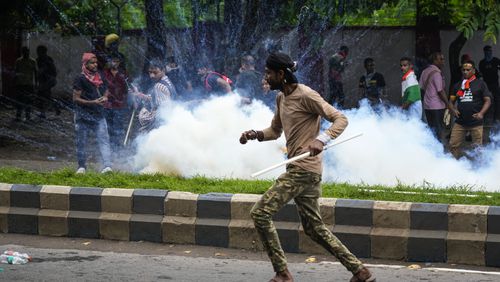 Protestors against the rape and murder of a resident doctor at a government hospital earlier this month, runs as police fire tear gas, in Kolkata, India, Tuesday, Aug. 27, 2024. (AP Photo/Bikas Das)