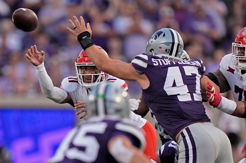 Arizona quarterback Noah Fifita passes around Kansas State defensive end Cody Stufflebean (47) during the first half of an NCAA college football game Friday, Sept. 13, 2024, in Manhattan, Kan. (AP Photo/Charlie Riedel)