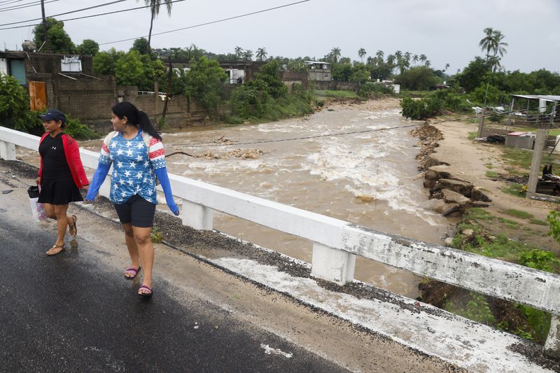 Women walk on a bridge in the aftermath of Hurricane John, in Acapulco, Mexico, Friday, Sept. 27, 2024. (AP Photo/Bernardino Hernandez)