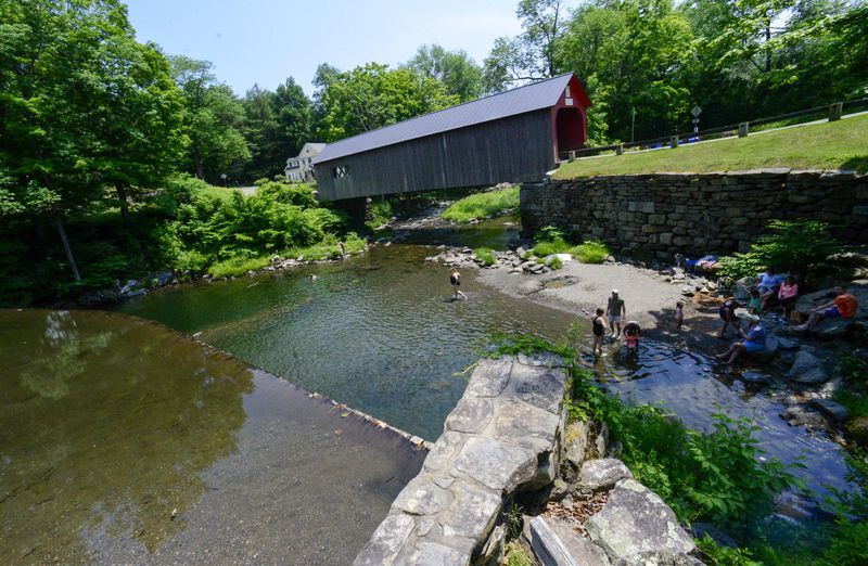 People cool down at the Green River Timber Crib Dam in Guilford, Vt., on Wednesday, June 19, 2024. (Kristopher Radder /The Brattleboro Reformer via AP)