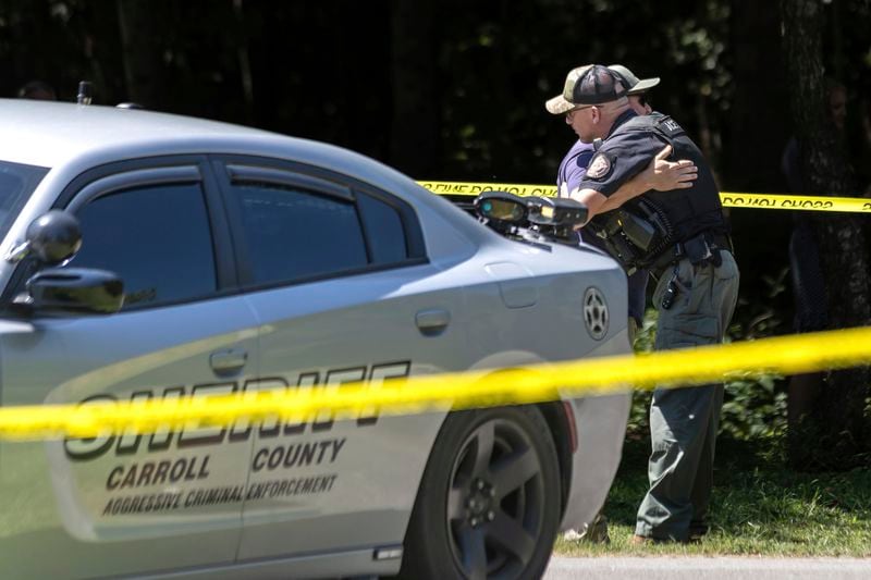 A member of the Carroll County sheriff's department, right, is hugged near the scene of a deadly shooting in Carrollton on Aug. 20, 2024. (John Spink/The Atlanta Journal-Constitution)