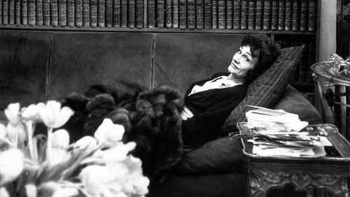 Gabrielle "Coco" Chanel, back in the fashion world after a lapse of 15 years, relaxes in her book-lined studio above her Paris salon April 21,1954.  (AP photo)