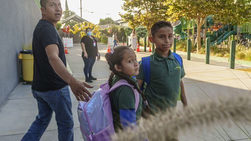 Roberto Garcia drops his children, Lily, 7, center, and Jack, 9, off for their first day of school in East Los Angeles on Wednesday, Aug. 14, 2024. (AP Photo/Damian Dovarganes)