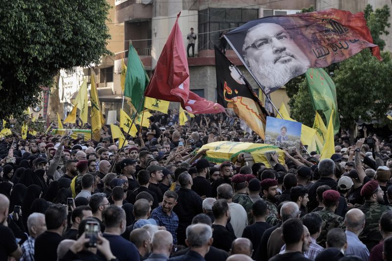 Mourners carry the coffins of Hezbollah fighters who were killed in Friday's Israeli strike, during their funeral procession in the southern suburb of Beirut, Lebanon, Saturday, Sept. 21, 2024. (AP Photo/Bilal Hussein)