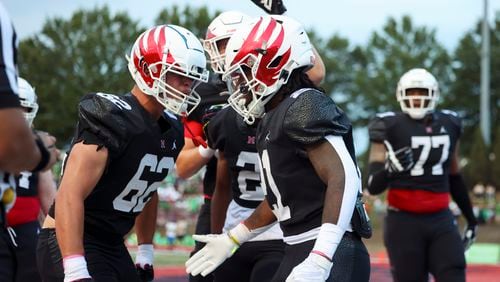 Milton running back TJ Lester (21, center) celebrates his rushing touchdown with offensive lineman Garrett Heinecke (62) during the first half against Buford at Milton High School, Friday, August 16, 2024, in Milton, Ga. This game is between two of the top teams in the state, as Milton is ranked No. 1 in Class 5A and Buford is ranked No. 1 in Class 6A. (Jason Getz / AJC)
