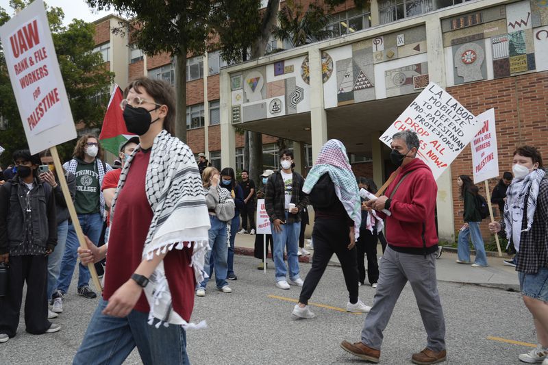 Pro-Palestinian protesters carry signs and march along the campus of the University of California in Los Angeles on Thursday, May 23, 2024. (AP Photo/Damian Dovarganes)