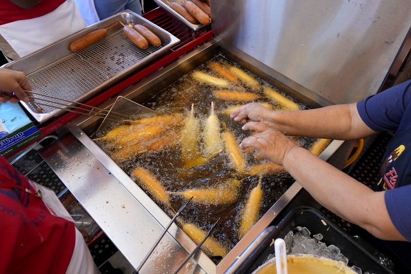 Luisa Lopez, right, helps prepare dozens of Fletchers corny dogs at their food booth at the State Fair of Texas in Dallas, Friday, Sept. 27, 2024. (AP Photo/Tony Gutierrez)