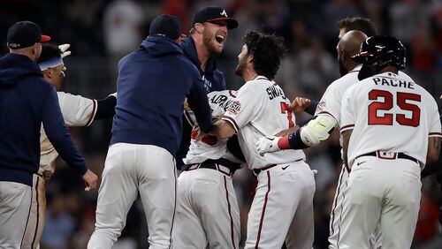 Braves infielder Ehire Adrianza (center) is mobbed by teammates after driving in the winning run in the 12th inning against the Philadelphia Phillies, in the early hours of Sunday, May 9, 2021, at Truist Park in Atlanta. (Ben Margot/AP)