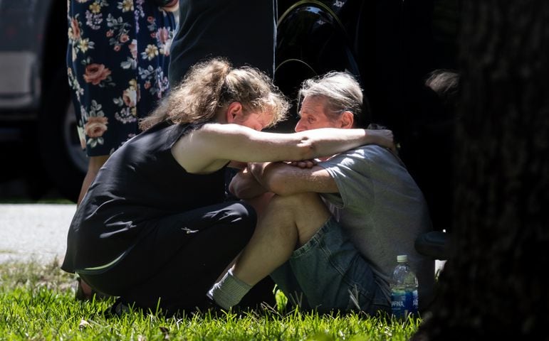 Family of the deceased suspect huddled nearby outside the crime scene tape. A Carroll County sheriff's deputy was taken to a hospital after being shot Tuesday morning, AUG. 20, 2024 according to officials. GBI agents are handling the investigation. Details are limited, but the deputy was flown to Grady Memorial Hospital in “very critical condition,” spokesperson Ashley Hulsey told The Atlanta Journal-Constitution at the scene. The suspected shooter is dead, Hulsey confirmed.  (John Spink/AJC)