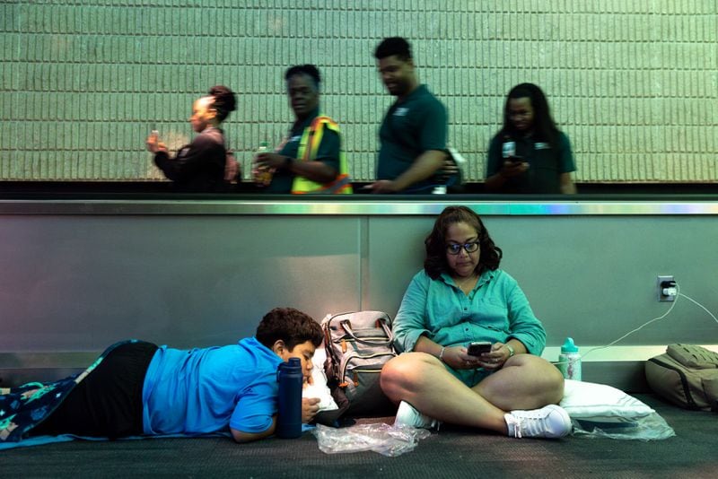 Monica Paz and Xavier Williams, 11, of Austin, Texas, try to rest at the Hartsfield-Jackson Atlanta International Airport domestic terminal late Saturday. (Arvin Temkar/The Atlanta Journal-Constitution)