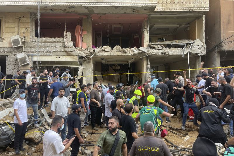 People gather near a damaged building at the scene of an Israeli missile strike in the southern suburbs of Beirut, Friday, Sept. 20, 2024. (AP Photo/Bilal Hussein)