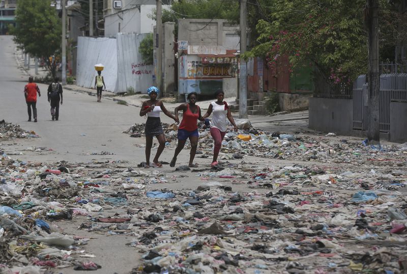 People walk down a street covered with trash in downtown Port-au-Prince, Haiti, Thursday, Sept. 5, 2024. (AP Photo/Odelyn Joseph)