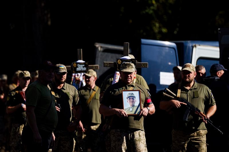 Ukrainian servicemen carry crosses and pictures of their comrades killed in a Russian rocket attack at a Ukrainian military academy, during their funeral ceremony in Poltava, Ukraine, Saturday Sept. 7, 2024. (AP Photo/Evgeniy Maloletka)