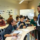 Kelsey Allen, front left, talks with her teacher, Rashad Brown, in their Advanced Placement African American Studies at Maynard Jackson High School on Friday, Feb 17, 2023.  (Jenni Girtman for The Atlanta Journal-Constitution)
