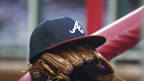 An Atlanta Braves hat and glove are shown near the steps of the dugout in between innings during their game against the Houston Astros at Truist Park, Friday, April 21, 2023, in Atlanta. The Braves lost to the Astros 6-4. Jason Getz / Jason.Getz@ajc.com)
