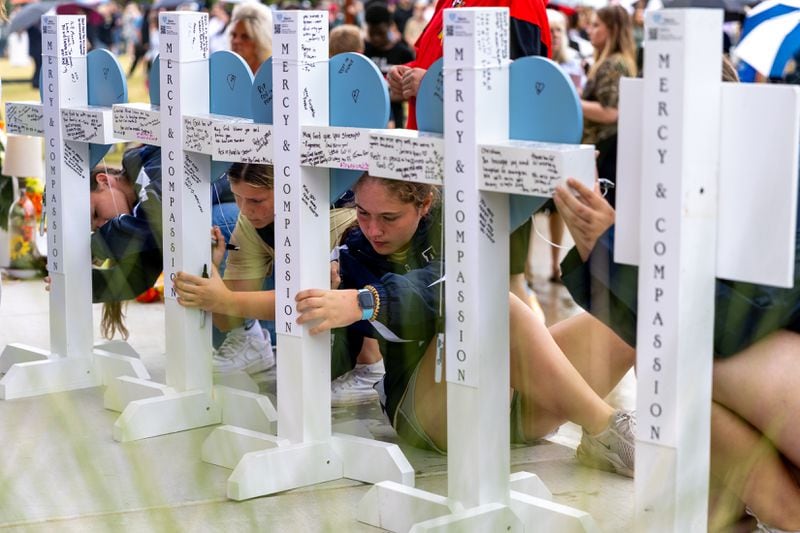 Mourners sign crosses at a vigil for the two students and two teachers killed at Apalachee High School.