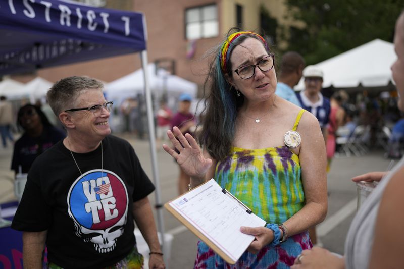 Illinois Rep. Kelly Cassidy, right, with her spouse, Candace Gingrich, left, talks with visitors to the Glenwood Avenue Arts Festival about canvassing efforts for the Democratic Party, Monday, Aug. 26, 2024, in Chicago. (AP Photo/Erin Hooley)