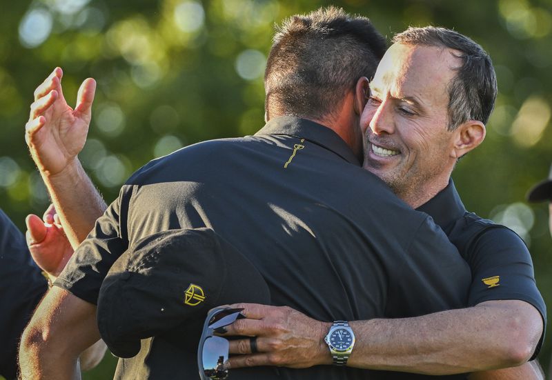 International team captain Mike Weir, right, hugs player Jason Day of Australia following their second round foursome match at the Presidents Cup golf tournament at the Royal Montreal Golf Club in Montreal, Friday, Sept. 27, 2024. (Graham Hughes/The Canadian Press via AP)