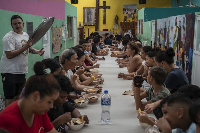 Migrants eat lunch at the Peace Oasis of the Holy Spirit Amparito shelter in Villahermosa, Mexico, Friday, June 7, 2024. After the head of Mexico's immigration agency ordered a halt to deportations in December, migrants have been left in limbo as authorities round up migrants across the country and dump them in the southern Mexican cities of Villahermosa and Tapachula. (AP Photo/Felix Marquez)