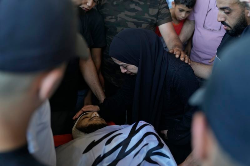 Mourners take a last look at the body of Yazeed Shafea, 22, wrapped with an Islamic Jihad flag, who was one of four Palestinians killed by an Israeli airstrike late Tuesday, during their funeral in the West Bank refugee camp of Nur Shams, near Tulkarem, Wednesday, July 3, 2024. Palestinian health officials say four Palestinians were killed by an Israeli airstrike in a refugee camp in the northern West Bank late Tuesday. Israel's military said an aircraft struck a group of militants who were planting explosives in Nur Shams refugee camp near Tulkarem. (AP Photo/Nasser Nasser)