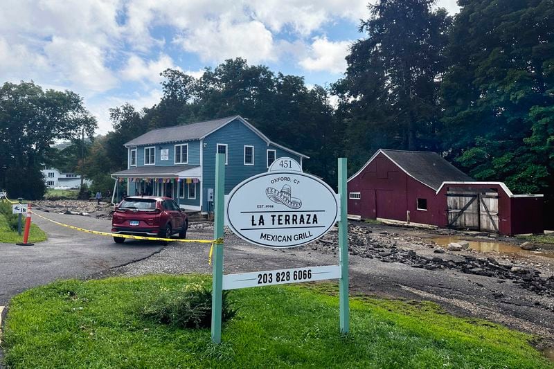 The driveway washed away and the basement flooded of Terraza Mexican Grill, owned by Isabel Perez, Javier Santos, in Oxford, Conn., when The Little River overflowed during heavy rains. (AP Photo/Dave Collins)