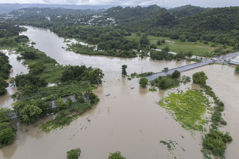 La Plata river floods a road after Tropical Storm Ernesto passed through Toa Baja, Puerto Rico, Wednesday, Aug. 14, 2024. (AP Photo/Alejandro Granadillo)