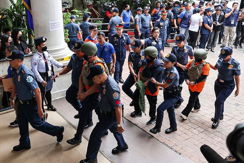 People, in green helmet, charged with human trafficking, enter the Pasig Regional Trial Court, walking after Apollo Carreon Quiboloy, a Filipino preacher, in Pasig City, Philippines, Friday, Sept. 13, 2024. (AP Photo/Gerard Carreon)