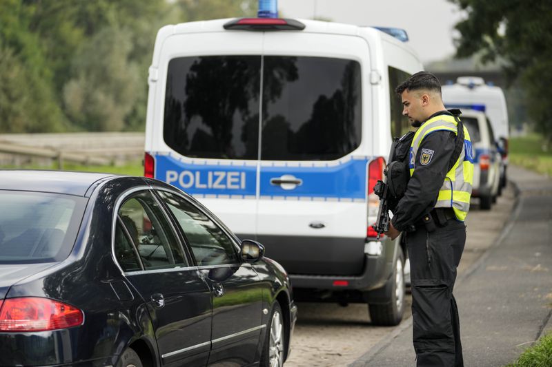 An armed German police officer checks the details of a French car near the border to Belgium in Aachen, Germany, Monday, Sept. 16, 2024, as Germany begins carrying out checks at all its land borders. (AP Photo/Martin Meissner)