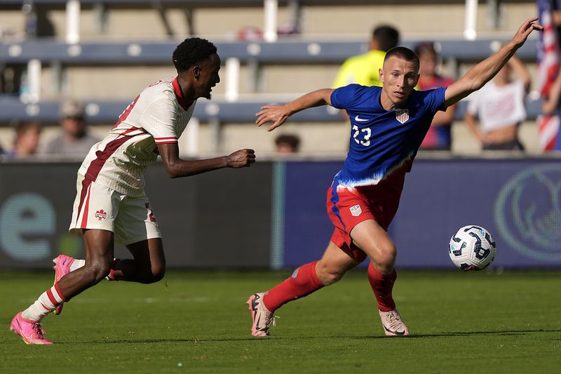 Canada midfielder Ali Ahmed, left, and United States defender Kristoffer Lund (23) chase after the ball during the second half of an international friendly soccer game, Saturday, Sept. 7, 2024, in Kansas City, Mo. Canada won 2-1. (AP Photo/Charlie Riedel)