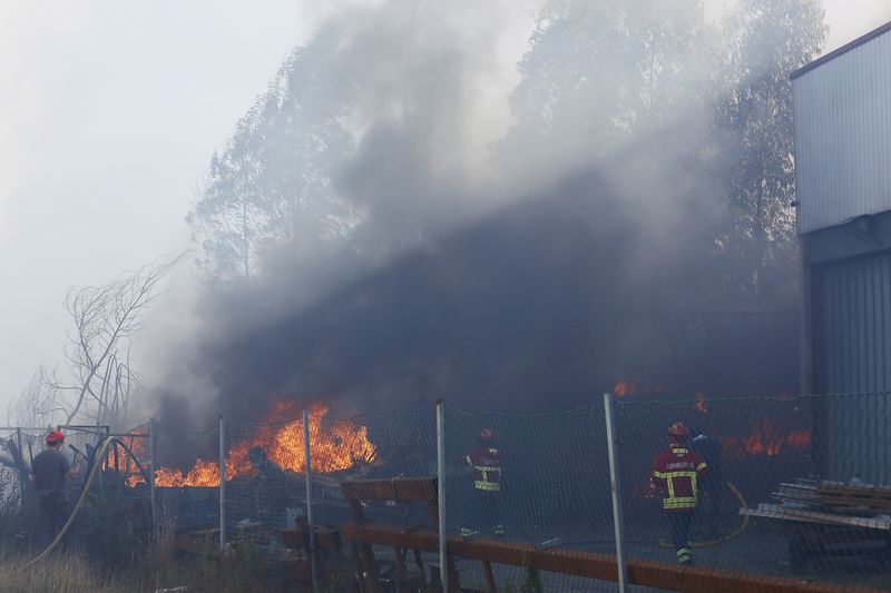 Firefighters work to control a fire next to a metalworking warehouse in Sever do Vouga, a town in northern Portugal that has been surrounded by forest fires, Monday, Sept. 16, 2024. (AP Photo/Bruno Fonseca)