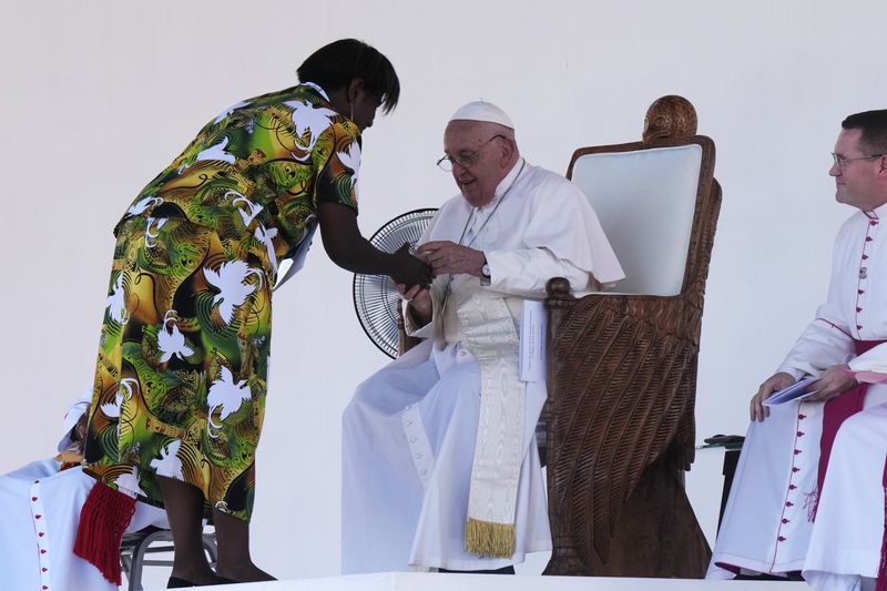 Pope Francis, center, interacts with a woman as gives an address during meeting with young people in the Sir John Guise Stadium in Port Moresby, Papua New Guinea, Monday, Sept. 9, 2024. (AP Photo/Mark Baker)