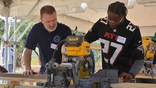 Atlanta Falcons safety Richie Grant uses a power saw, with some guidance from a PlayTown Suwanee volunteer, on Tuesday. Members of the Falcons organization, including some players, came out to help PlayTown Suwanee build its new playground at the Suwanee Town Center on Main. (Photo Courtesy of Curt Yeomans)