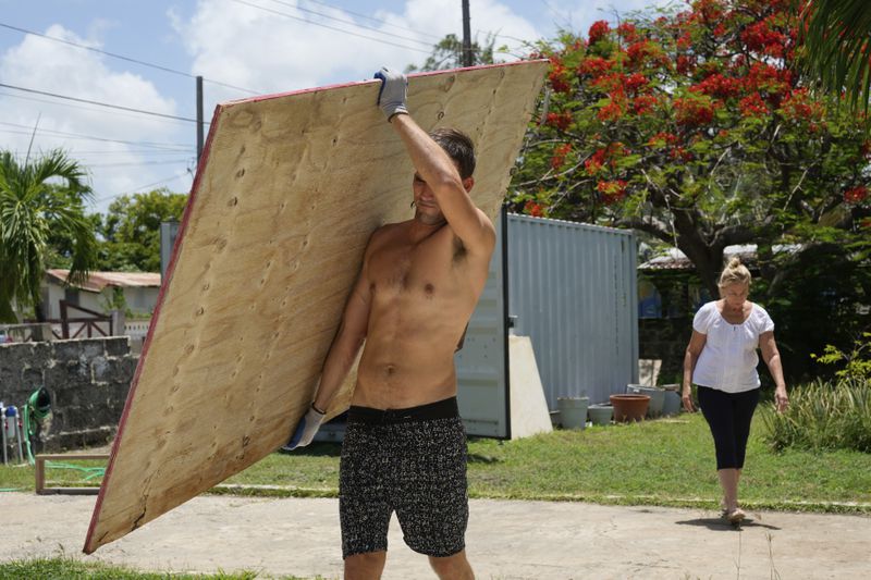 A resident carries wood to cover his house's windows in preparation for Hurricane Beryl, in Bridgetown, Barbados, Sunday, June 30, 2024. (AP Photo/Ramon Espinosa)