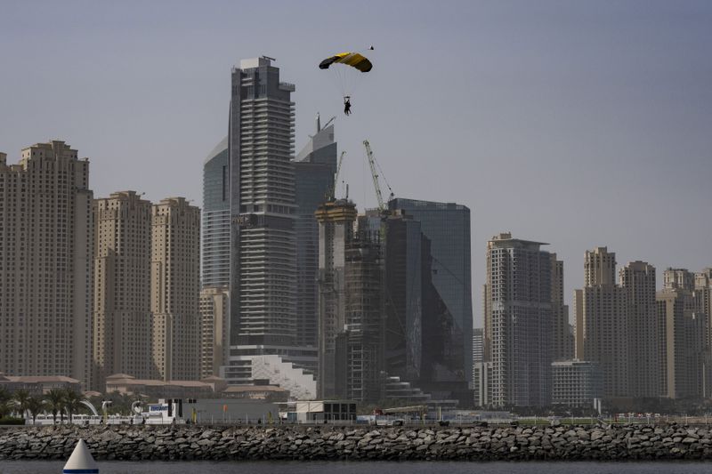 Sky divers glides a parachute as they prepare to land along a route with the skyscrapers of Dubai Marina looming beneath them, United Arab Emirates, Tuesday, Aug. 13, 2024. (AP Photo/Altaf Qadri)