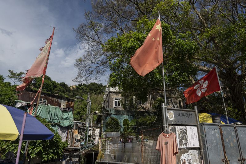 The flags of China and the Hong Kong Special Administrative Region (HKSAR) are flown at the entrance to the Cha Kwo Ling village in east Kowloon, Hong Kong, Sunday, Aug. 25, 2024. (AP Photo/Chan Long Hei)