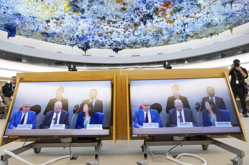 Screens show U.N. High Commissioner for Human Rights Volker Turk, left, and Morocco's Ambassador Omar Zniber, President of the Human Rights Council, 2nd left, as they attend the opening of the 57th session of the Human Rights Council at the European headquarters of the United Nations in Geneva, Switzerland, Monday, Sept. 9, 2024. (Salvatore Di Nolfi/Keystone via AP)