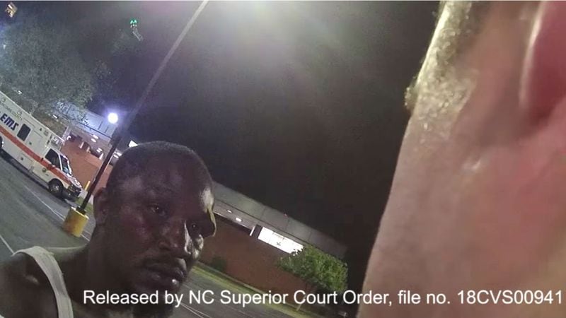 In a still image from body camera footage released Monday by Asheville, N.C., police officials, Johnnie Rush's injuries are visible as he speaks to Officer Christopher Hickman outside a hospital the morning of Aug. 25, 2017. Rush, 33, was walking home from work that morning when Hickman and his partner accused the Cracker Barrel employee of jaywalking. The subsequent confrontation, caught on camera and shared by a local newspaper in February, led to community outrage and a felony charge of assault by strangulation against Hickman, who resigned in January.