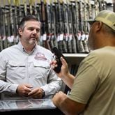 Adventure Outdoors general manager and part-owner Eric Wallace, left, helps Bobby Gibbs decide on a potential gun purchase in Smyrna on Tuesday, July 23, 2024. Sales are up substantially, according to Wallace. “A lot of our customers are saying that if the Secret Service, which is known to be one of the best law enforcement agencies in the world, can’t protect a former president, how is our government going to protect us if something serious were to happen?” Wallace said.  (Steve Schaefer / AJC)