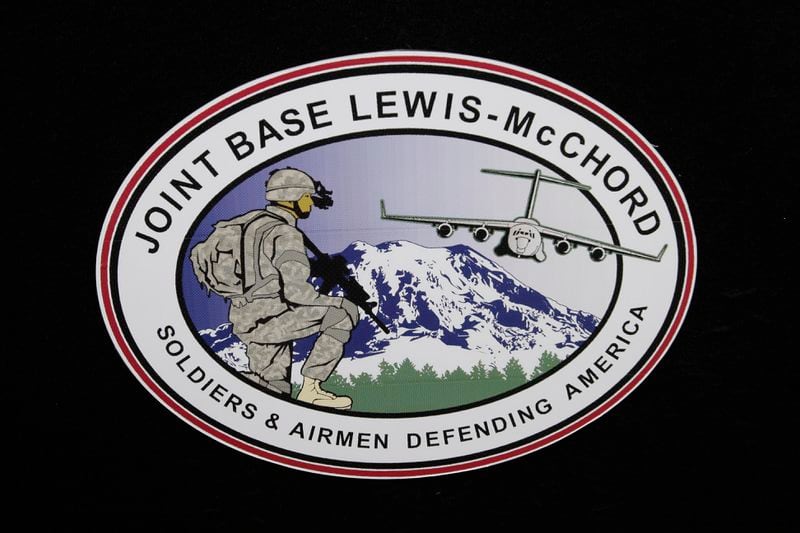 FILE - The logo of Joint Base Lewis-McChord is seen at a ceremony marking the merger of Fort Lewis and McChord Air Force Base into Joint Base Lewis-McChord, Feb. 1, 2010, in Washington state. Fifteen current or retired Joint Base Lewis-McChord servicemen who say the Army failed to protect them from a military doctor who's been charged with sexual abuse are seeking $5 million in damages for the emotional distress they say they've suffered. (AP Photo/Ted S. Warren, File)
