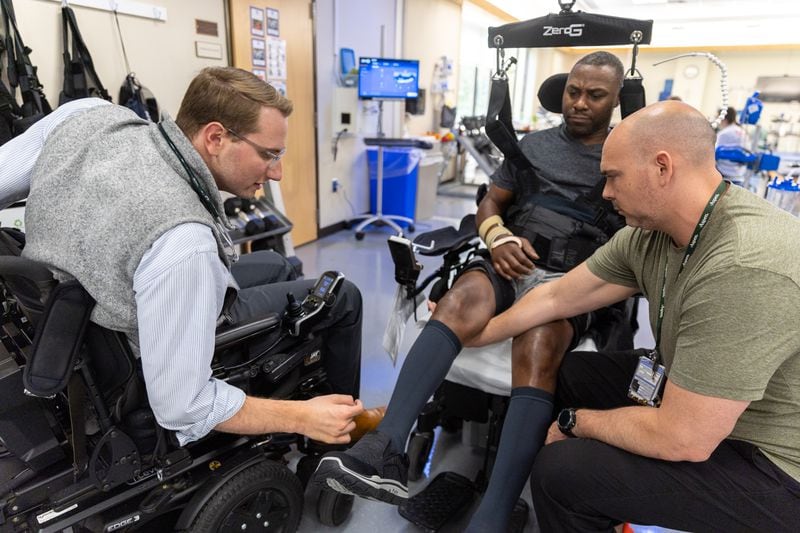 Dr. Woody Morgan, left, checks on patient Nathan Pope, 49, at Shepherd Center in September. Morgan treats newly injured patients, and works with a team of therapists to help patients achieve the highest level of function and independence possible. (Arvin Temkar / arvin.temkar@ajc.com)