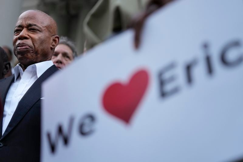 New York City Mayor Eric Adams, left, is surrounded by faith leaders and other supporters during a rally and prayer vigil on the steps of City Hall in New York, Tuesday, Oct. 1, 2024. (AP Photo/Seth Wenig)