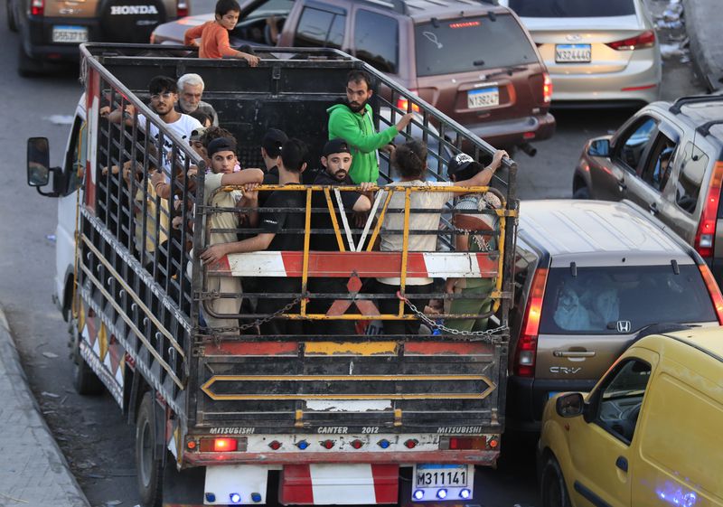 Lebanese citizens who fled on he southern villages amid ongoing Israeli airstrikes Monday, stand on a pickup at a highway that links to Beirut city, in the southern port city of Sidon, Lebanon, Tuesday, Sept. 24, 2024. (AP Photo/Mohammed Zaatari)