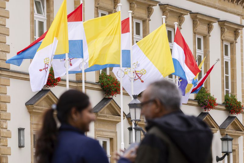 Flags of Vatican City and Luxembourg wave outside the Luxembourg City Hall a day before for the trip of Pope Francis to Luxembourg and Belgium, Wednesday, Sept. 25, 2024, (AP Photo/Geert Vanden Wijngaert)