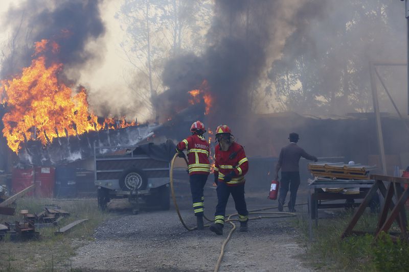 Firefighters work to control a fire at a metalworking warehouse in Sever do Vouga, a town in northern Portugal that has been surrounded by forest fires, Monday, Sept. 16, 2024. (AP Photo/Bruno Fonseca)