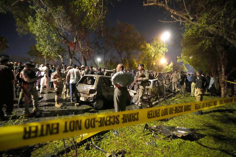 Security officials examine the site of an explosion that caused injures and destroyed vehicles at outside the Karachi airport, Pakistan, Monday, Oct. 7, 2024. (AP Photo/Fareed Khan)