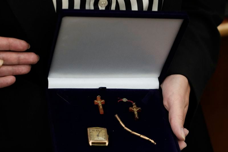 A relative shows amber crucifixes and jewelry that were confiscated by Nazi Germans from Stanislawa Wasilewska, who was captured by Nazi troops during Warsaw Uprising in 1944 and taken to a forced labor camp. The items that had been stored at Germany's Arolsen Archives, were returned to Wasilewska's relatives in a ceremony in Warsaw, Poland, on Tuesday, Sept. 10, 2024, in which 10 other families also had belongings of their relatives returned. (AP Photo/Czarek Sokolowski)