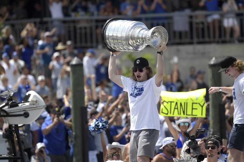 FILE - Tampa Bay Lightning defenseman Mikhail Sergachev hoists the Stanley Cup while riding on a boat with goaltender Andrei Vasilevskiy, right, during the NHL hockey Stanley Cup champions' Boat Parade, Monday, July 12, 2021, in Tampa, Fla. The Utah Hockey Club made a big splash at its first draft, acquiring two-time Stanley Cup-winning defenseman Mikhail Sergachev from the Tampa Bay Lightning. (AP Photo/Phelan M. Ebenhack, File)